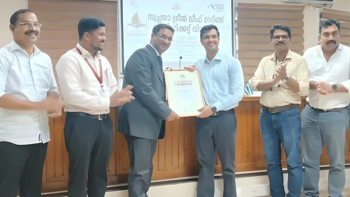 Six men are standing, with two in the center holding the certificate 