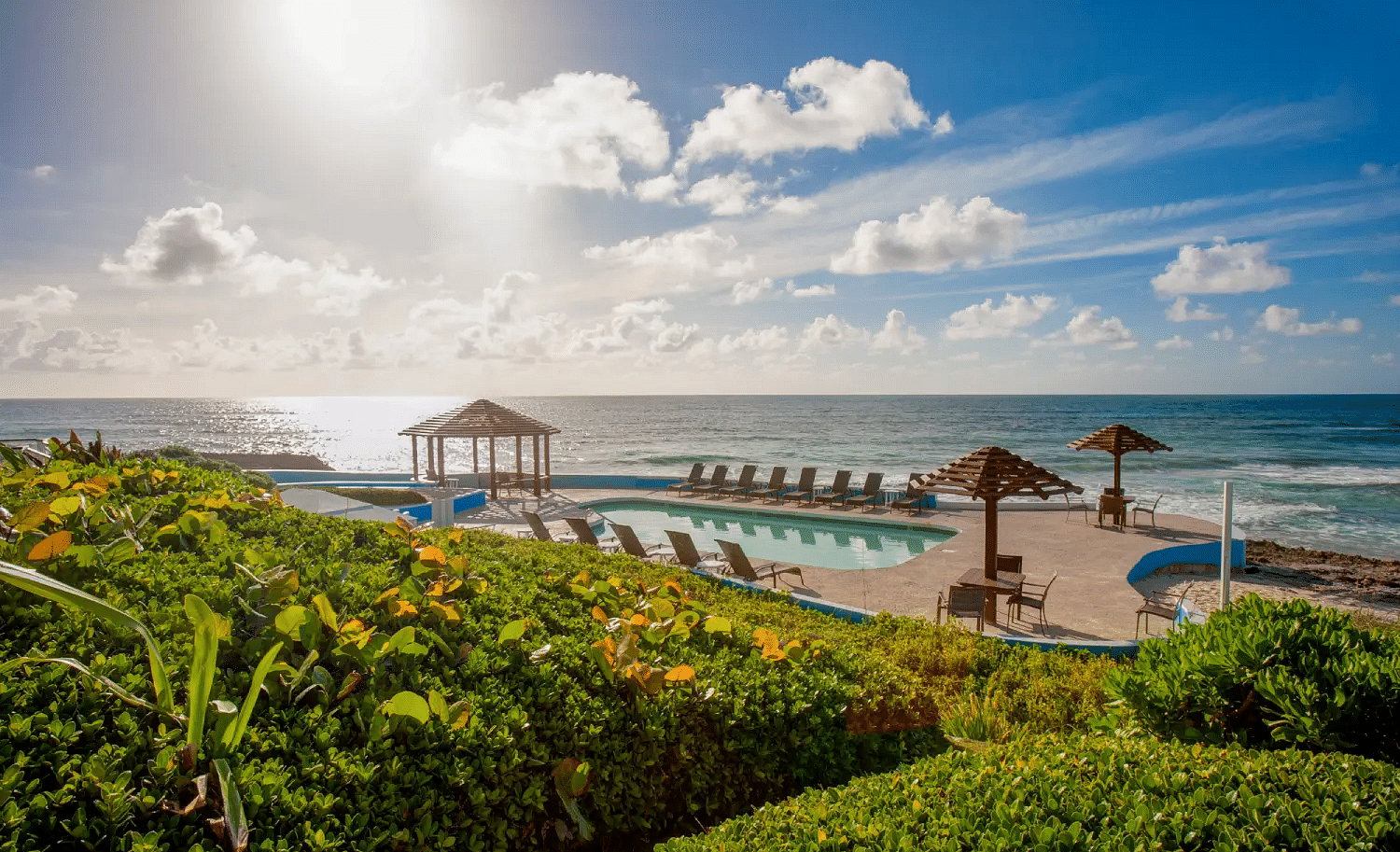 Wooden deck with thatched umbrellas and lounge chairs by the beach | Abaco Inn