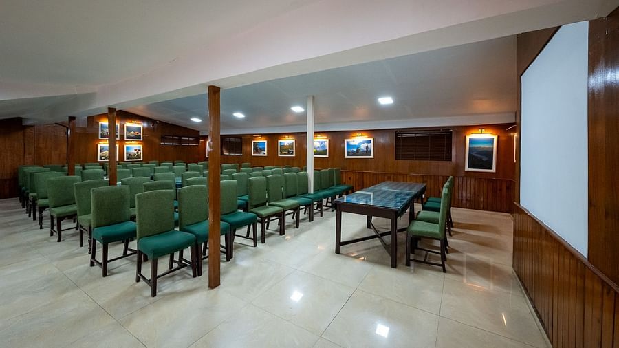 Side view of spacious conference hall with rows of green chairs at Himalaya Hotel, Nainital