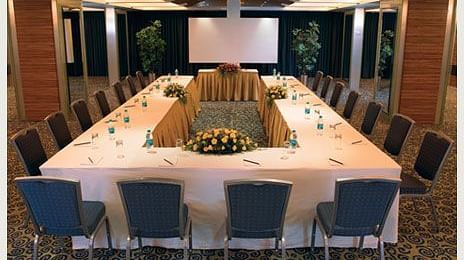 Shot of the expansive conference room in Mirage Hotel featuring a large table with chairs around it along with a projector on the wall. | Mirage Hotel