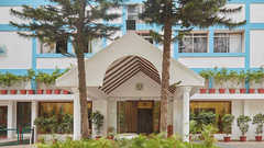 The building entrance of the best resort in Bangalore, with steps, pillars, and potted plants | Ramanashree California Resort