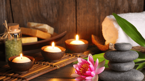 a spa set up with candles, flowers and hot stones
