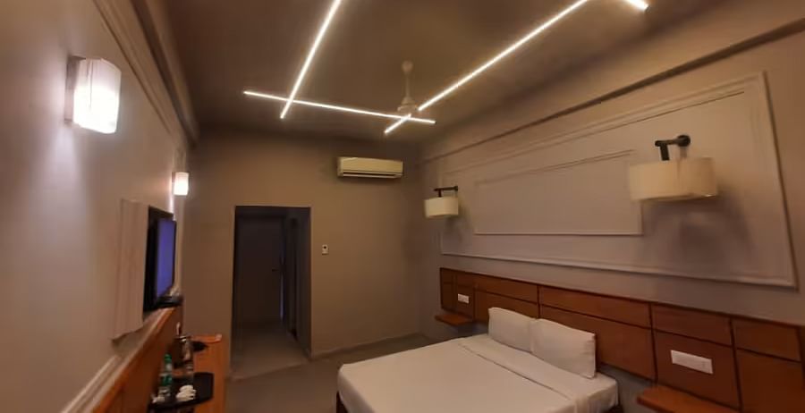 View of a stylish hotel room with a bed, tv mounted on the wall, and a lamp featuring a sleek design - Max Hotel Prayagraj.