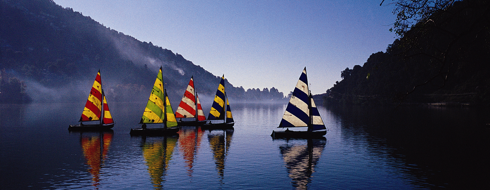 Colorful paddleboats on a lake at sunset.