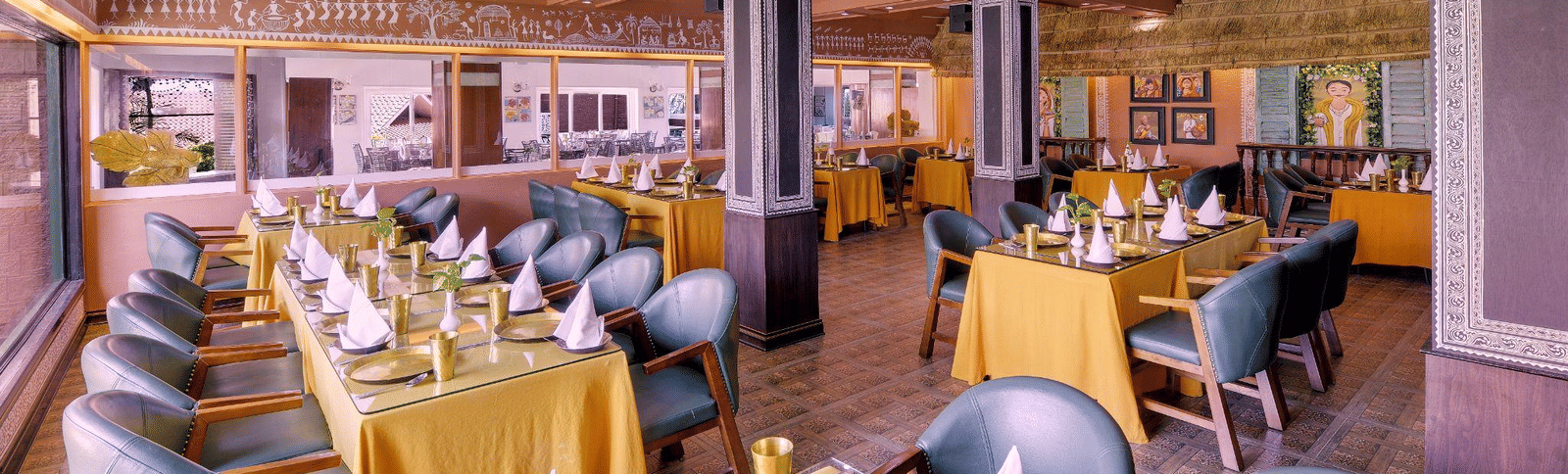 Bright, formal dining hall with long tables set with yellow tablecloths and high-backed chairs, ready for a banquet or large event