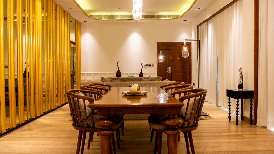 A spacious dining room with a long wooden table, surrounded by modern chairs and wooden paneling on the walls.