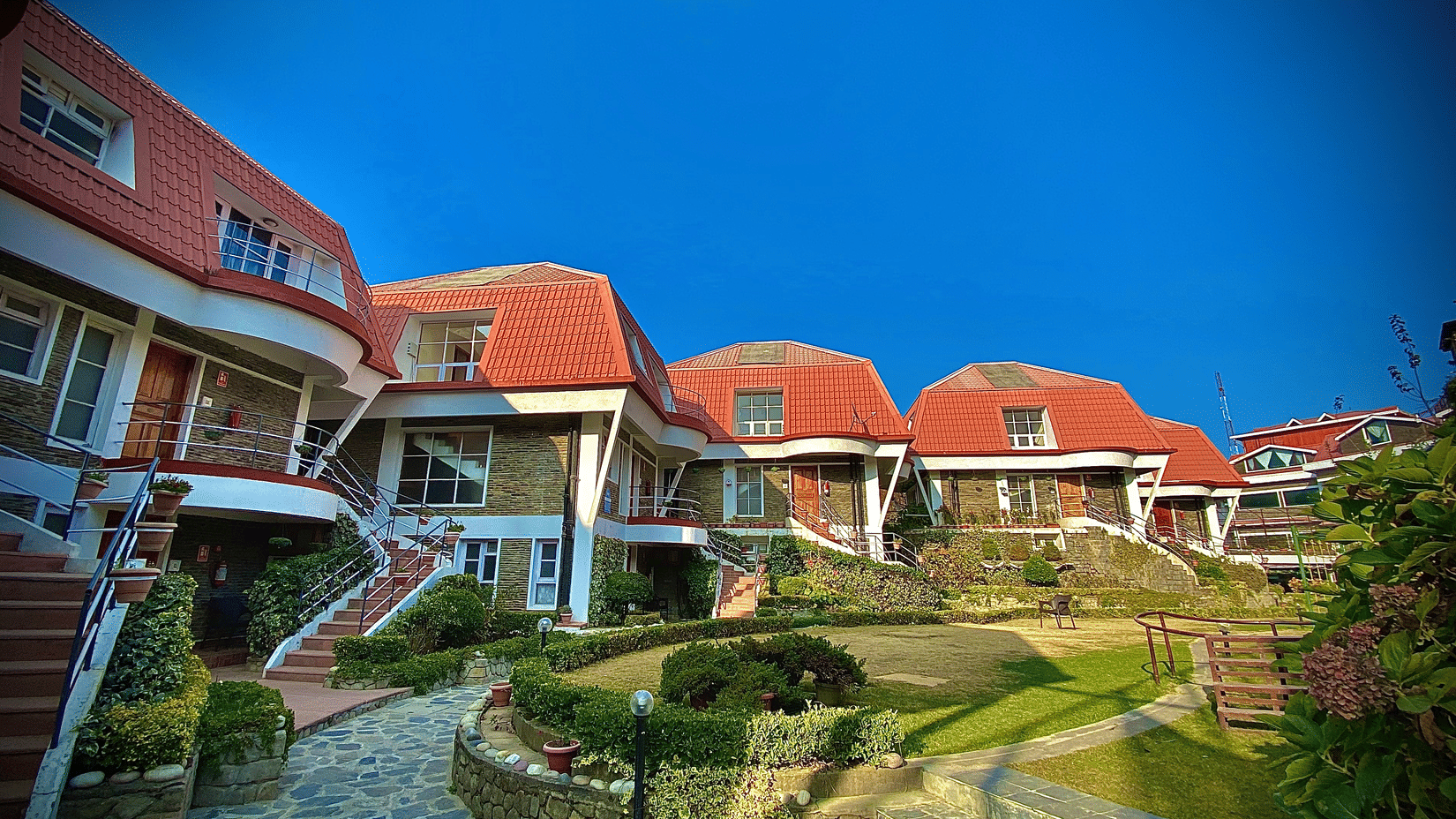 attic style cottages at Marigold Sarovar Portico, Mashobra Shimla. Each of these are three storey buildings with stairs and has a garden lawn at the centre.