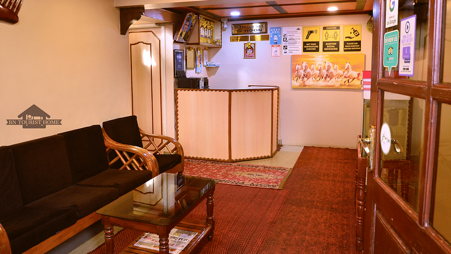 The reception desk at BN Tourist Home, Ooty, decorated with colourful posters and framed artwork - BN Tourist Home, Ooty