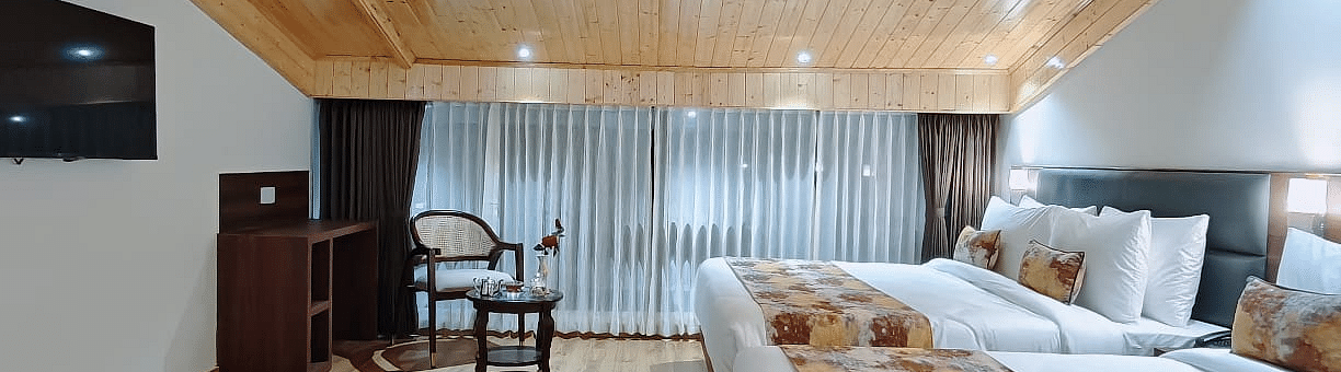 A hotel room with two beds and patterned runners, a tv on the wall and a hallway view, showing the room's layout - Sumitel JB Park, Darjeeling
