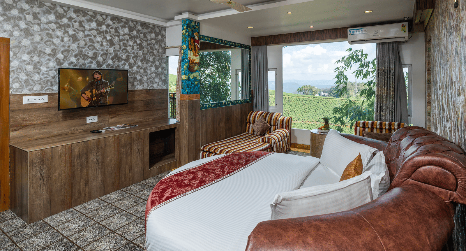A bedroom in Family Jacuzzi Room in Parakkat Nature Hotel and Resorts, Munnar, featuring a round bed, a flat-screen TV, a ceiling fan, and an opening to a private balcony.