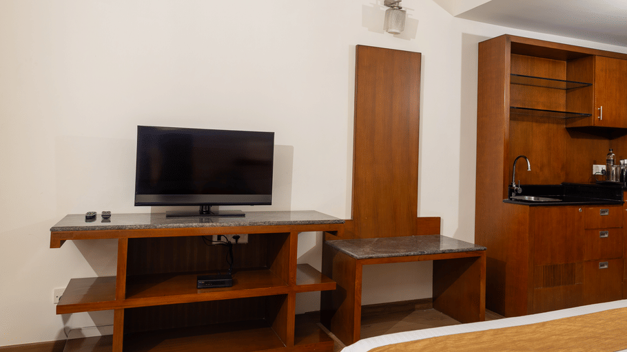 Hotel room desk area at Featherlite Evoma Hotel with a wooden TV console, a work desk and wooden flooring throughout the whole space.
