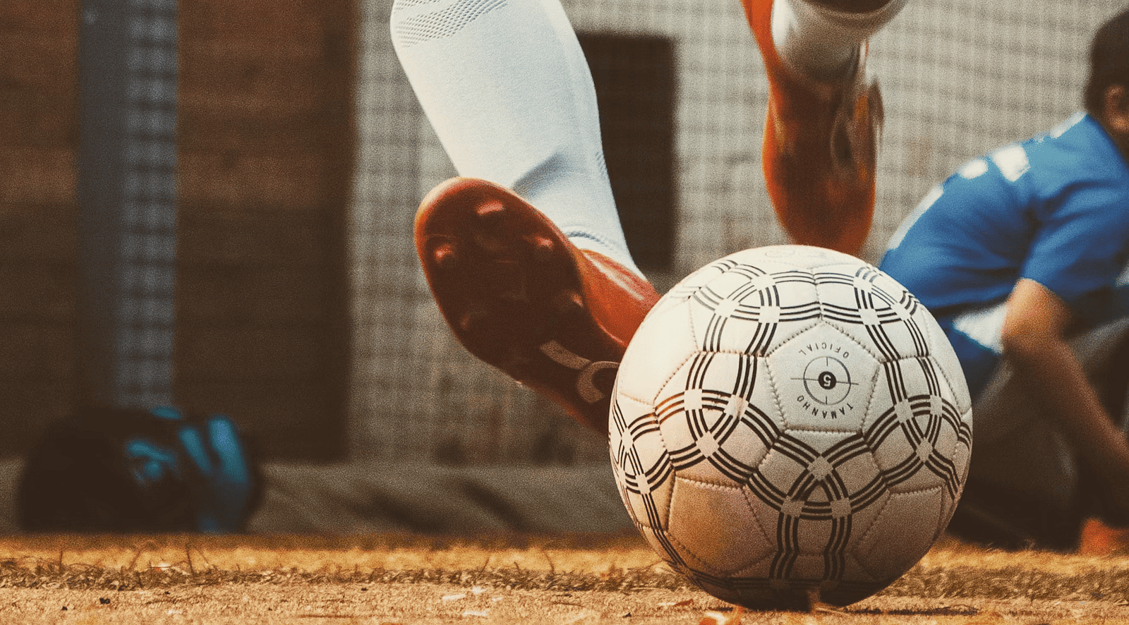 A worn soccer ball rests on the ground, with a foot visible, suggesting a game or practice at Nirantara Resort & Spa.