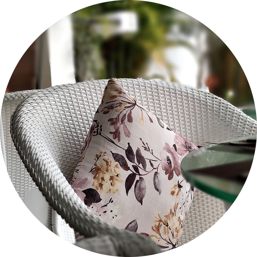 Close-up of a wicker chair with a floral cushion on a patio.