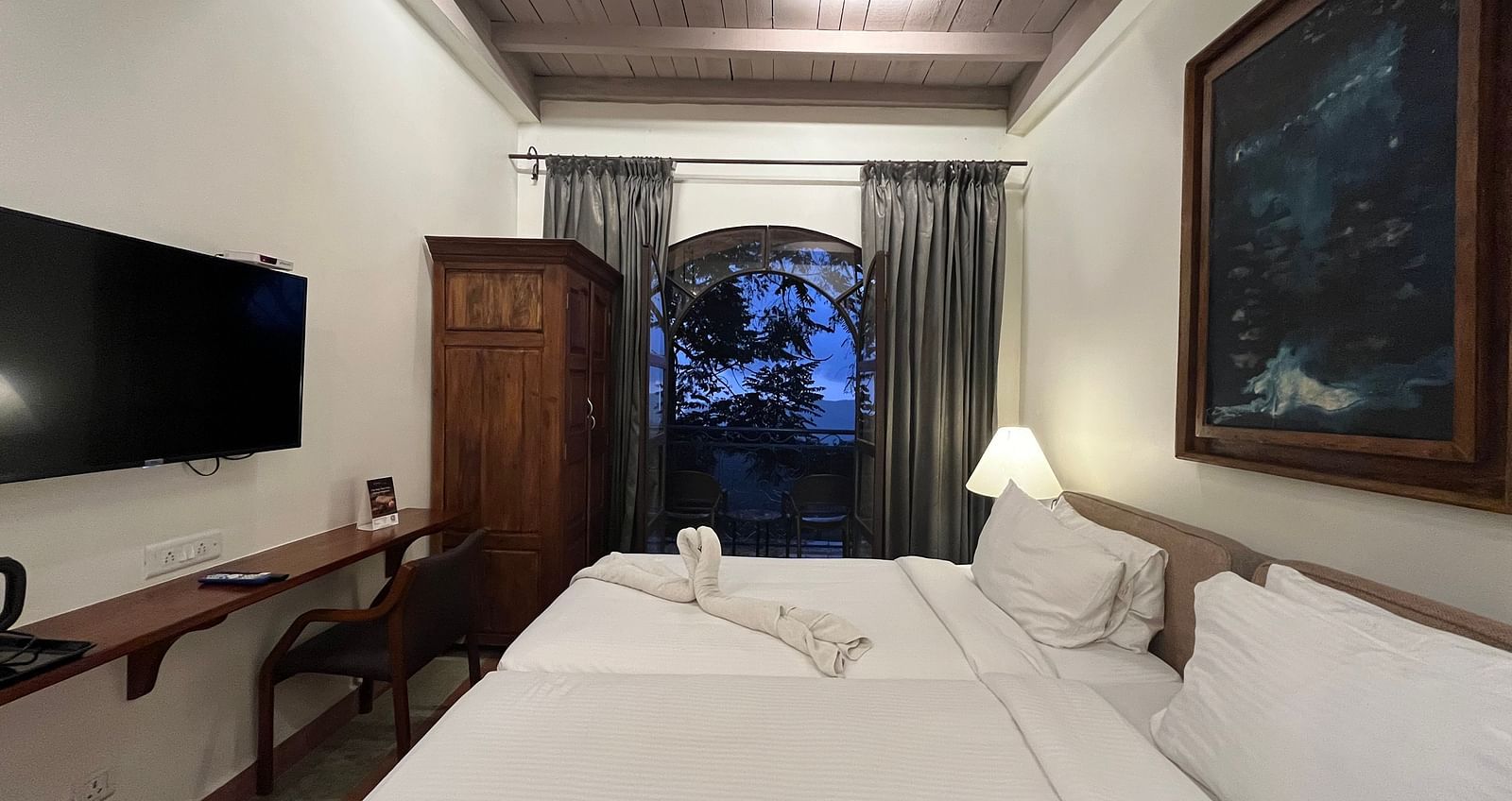 An image of two large beds, a flat screen TV, cupboard, and a window |  Mango Hill, Yercaud