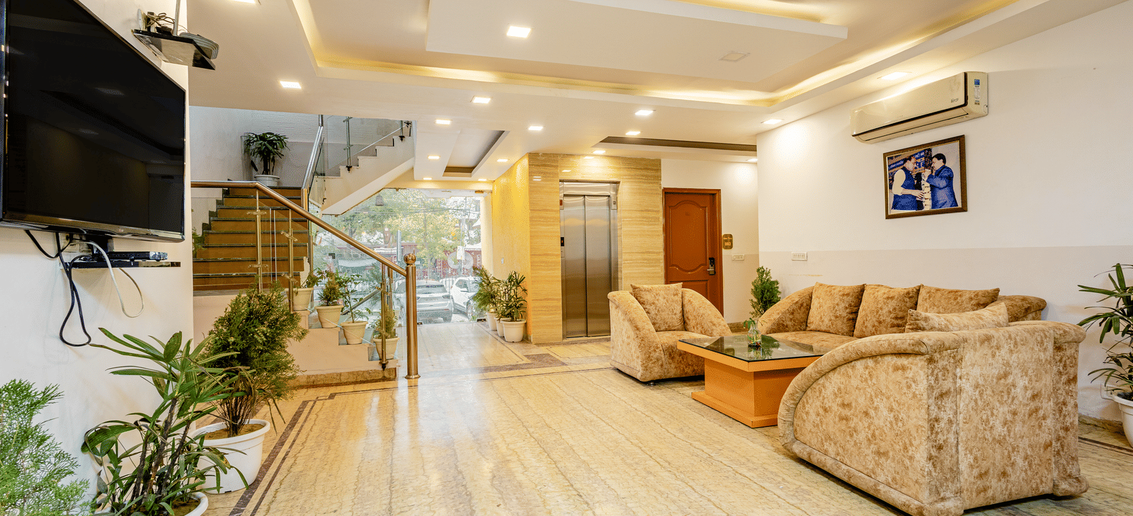 A wide view of the sofas and TV screen in the lobby of Lime Tree Hotels and Banquet Hall Near Huda Metro, Gurgaon