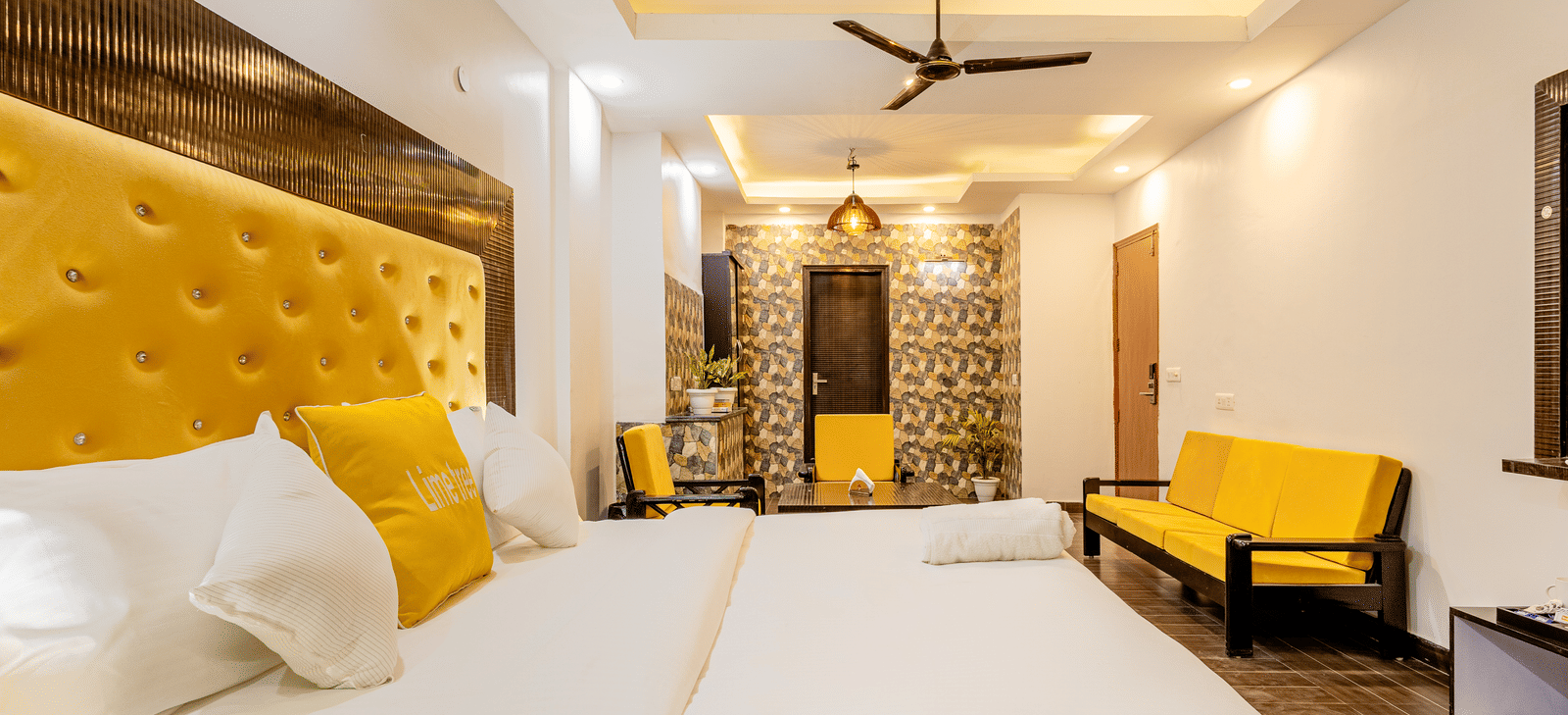 Side view of the king size bed and the living area in the Suite at Lime Tree Hotels and Banquet Hall Near Huda Metro, Gurgaon