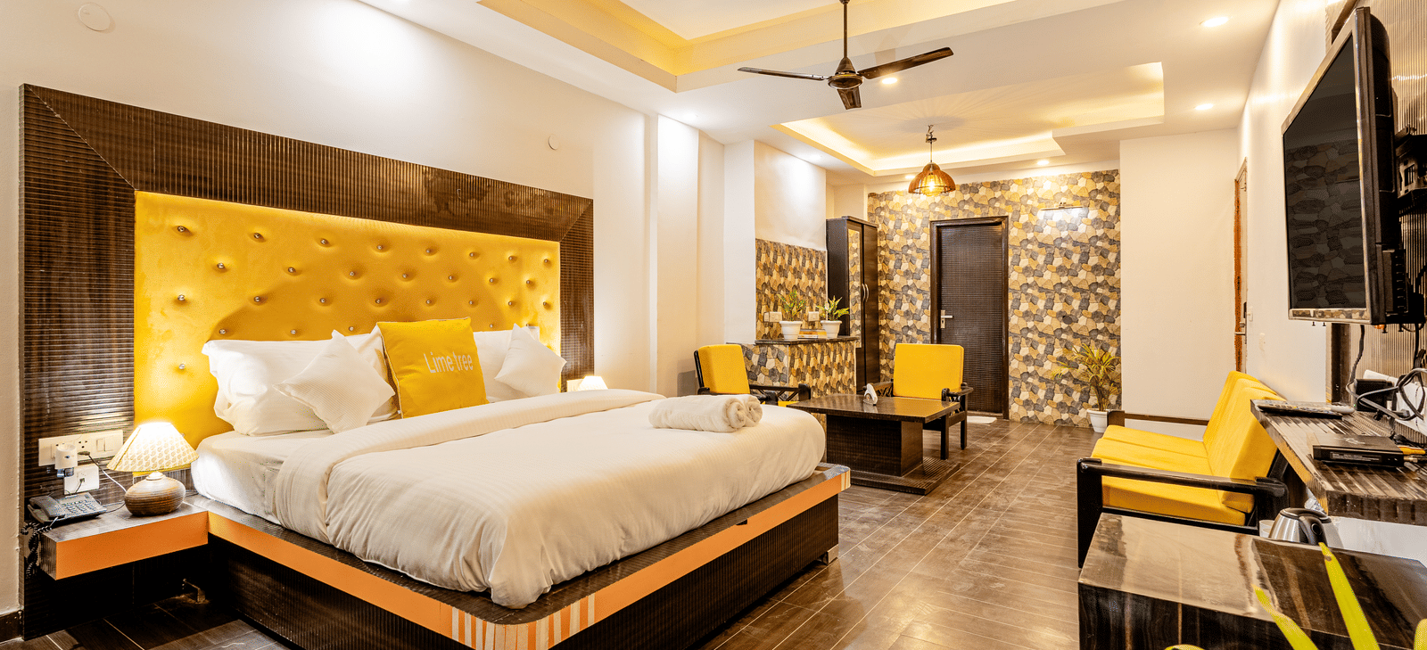 side view of the king size bed, the living area and a television in the suite at Lime Tree Hotels and Banquet Hall Near Huda Metro, Gurgaon