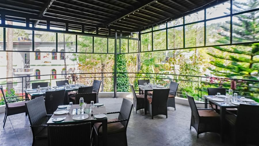 Covered outdoor dining area with tables and chairs neatly arranged at WOW Bungalow, Yercaud. 
