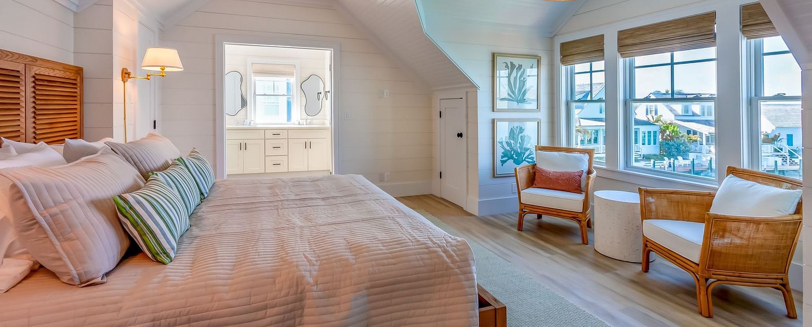 a bedroom at Abaco Inn with a huge bed, wooden floor, chairs, table, ceiling fan and windows overlooking the sea view.