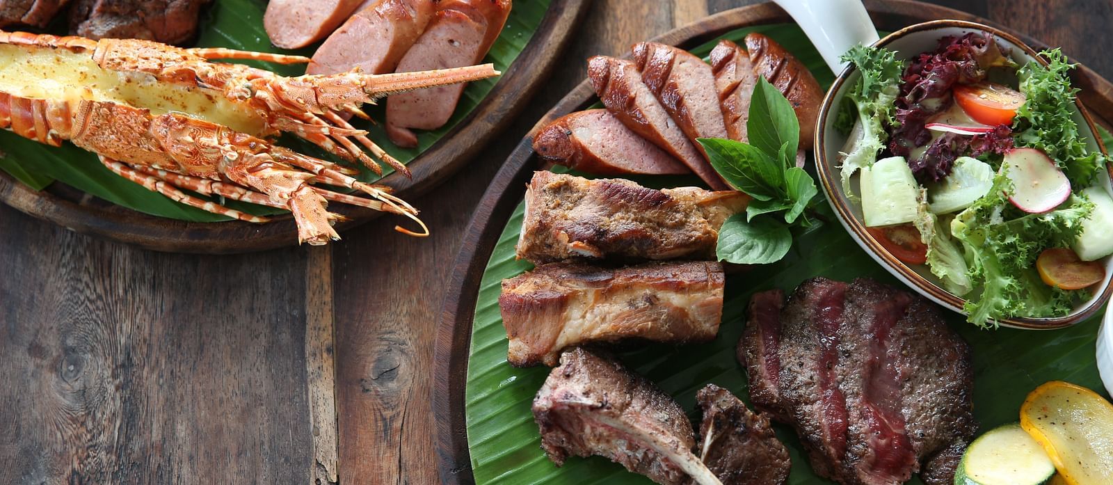A platter of grilled meats and seafood on banana leaves - Alibu Resort Nha Trang
