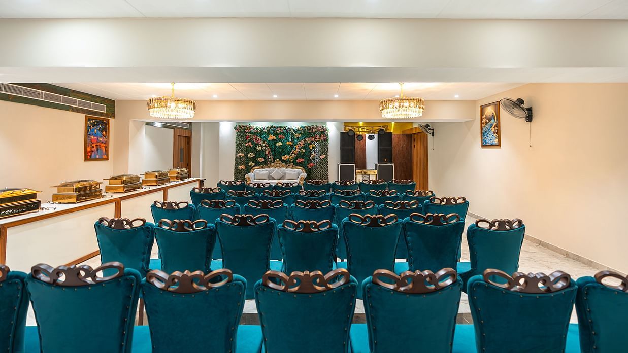 A banquet hall with blue chairs arranged and a stage -Pearl Hall
