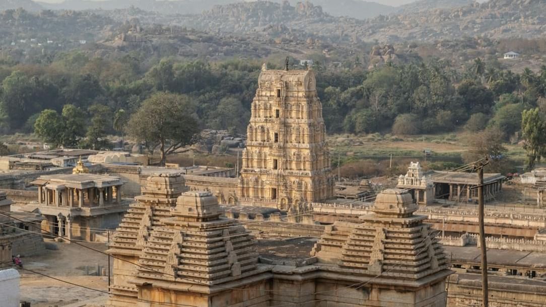 An ancient temple with a tall tower stands amidst a rural landscape with hills in the background.