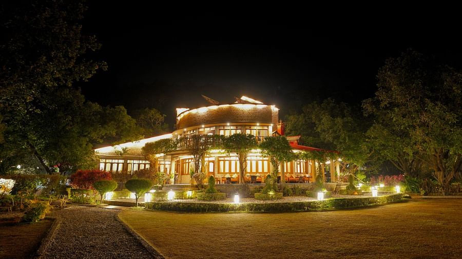 A multi-level building with lights, nestled in a forested hillside at night.