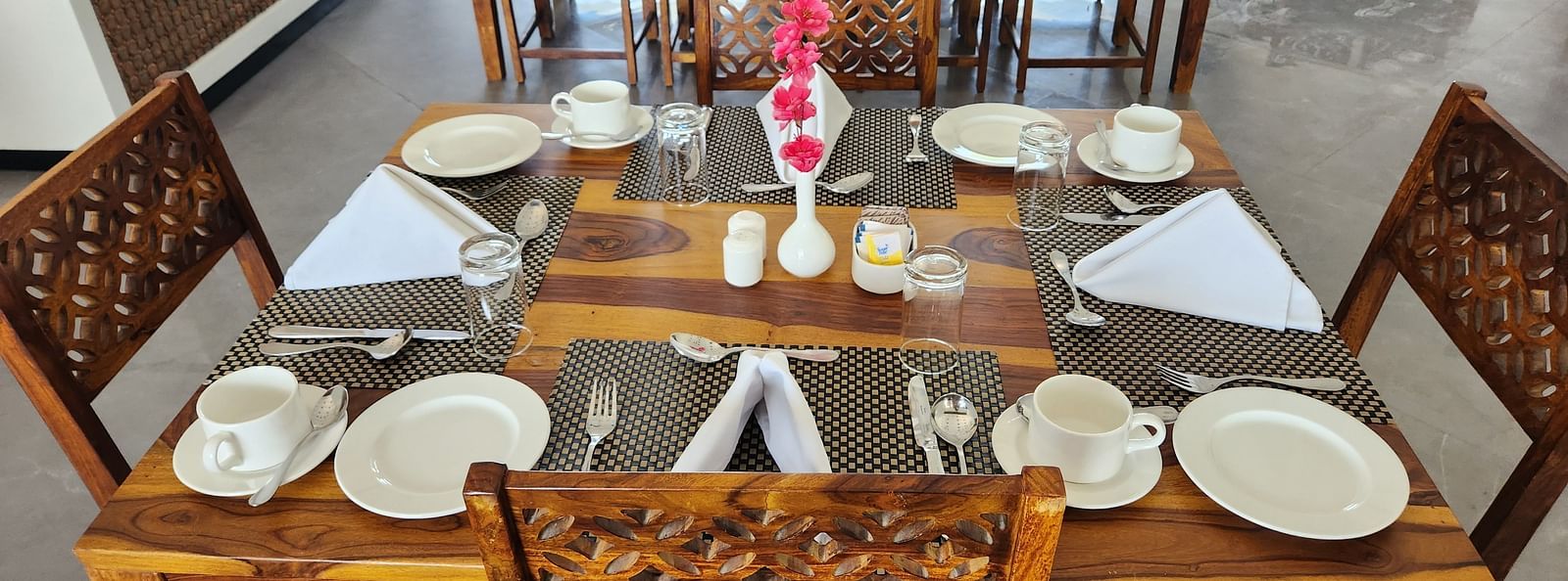 An aerial view of an indoor dining table set with plates and cutlery at the Bamboo Saa Mulberry Resort, Pushkar.