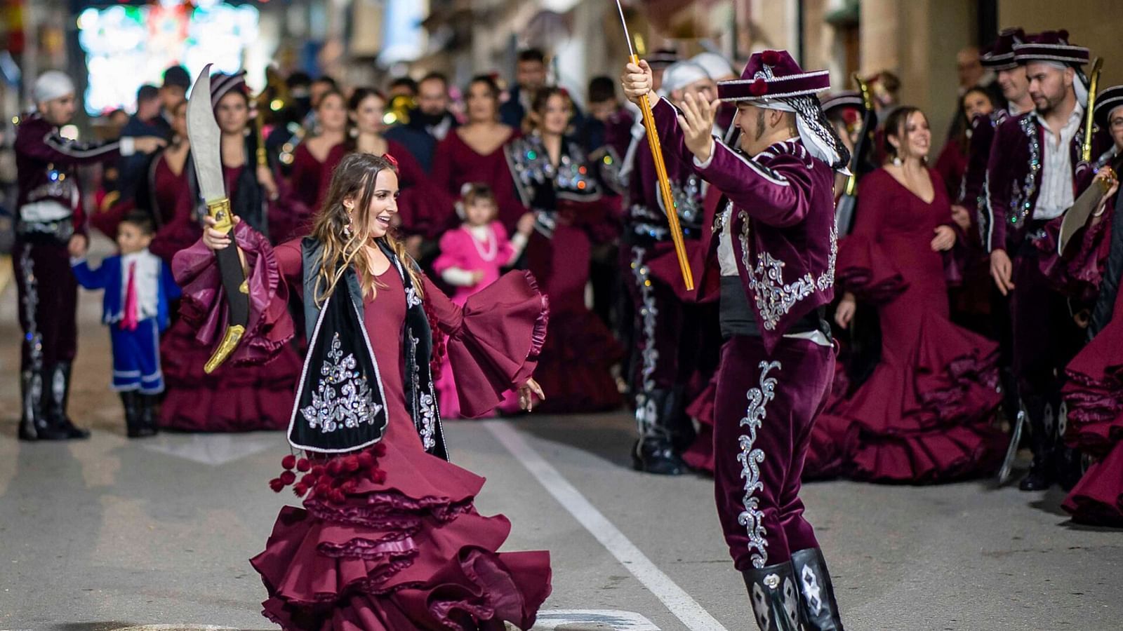 An overview of a couple of dancers on the street in elaborate clothing, dancing on the street.