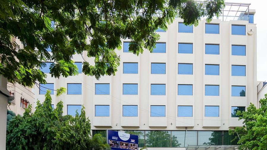  A facade image of the Marasa Sarovar Portico, Rajkot with trees around.