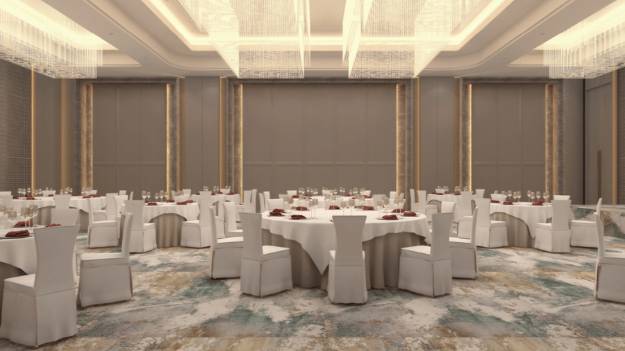 Banquet hall at Tulip Inn Bidar with 8 round dining tables, chairs with fabric covers, lit ceiling fixtures, and patterned carpet flooring.