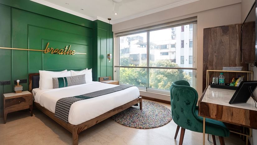A cozy bedroom featuring a bed, a table with two chairs, and a window offering a view outside