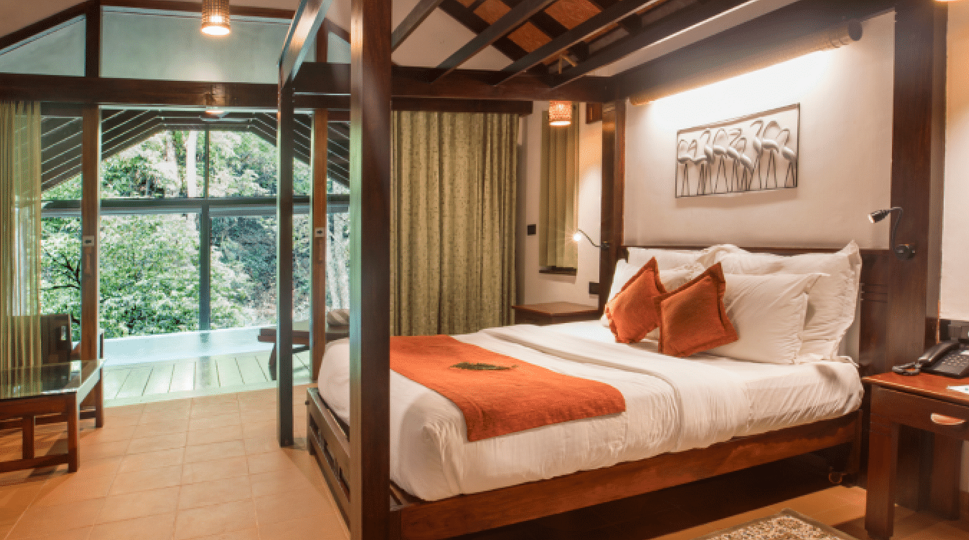 A side view of a bed in a room that has forest views | Vythiri Resort, Wayanad