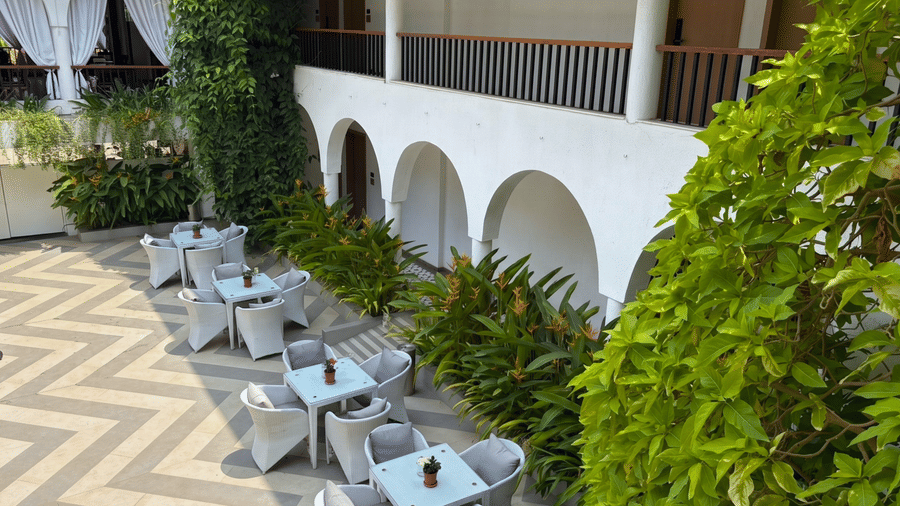 An elevated view of outdoor tables, chairs, potted plants arranged in a paved courtyard at Bougainvillea, Alibaug.