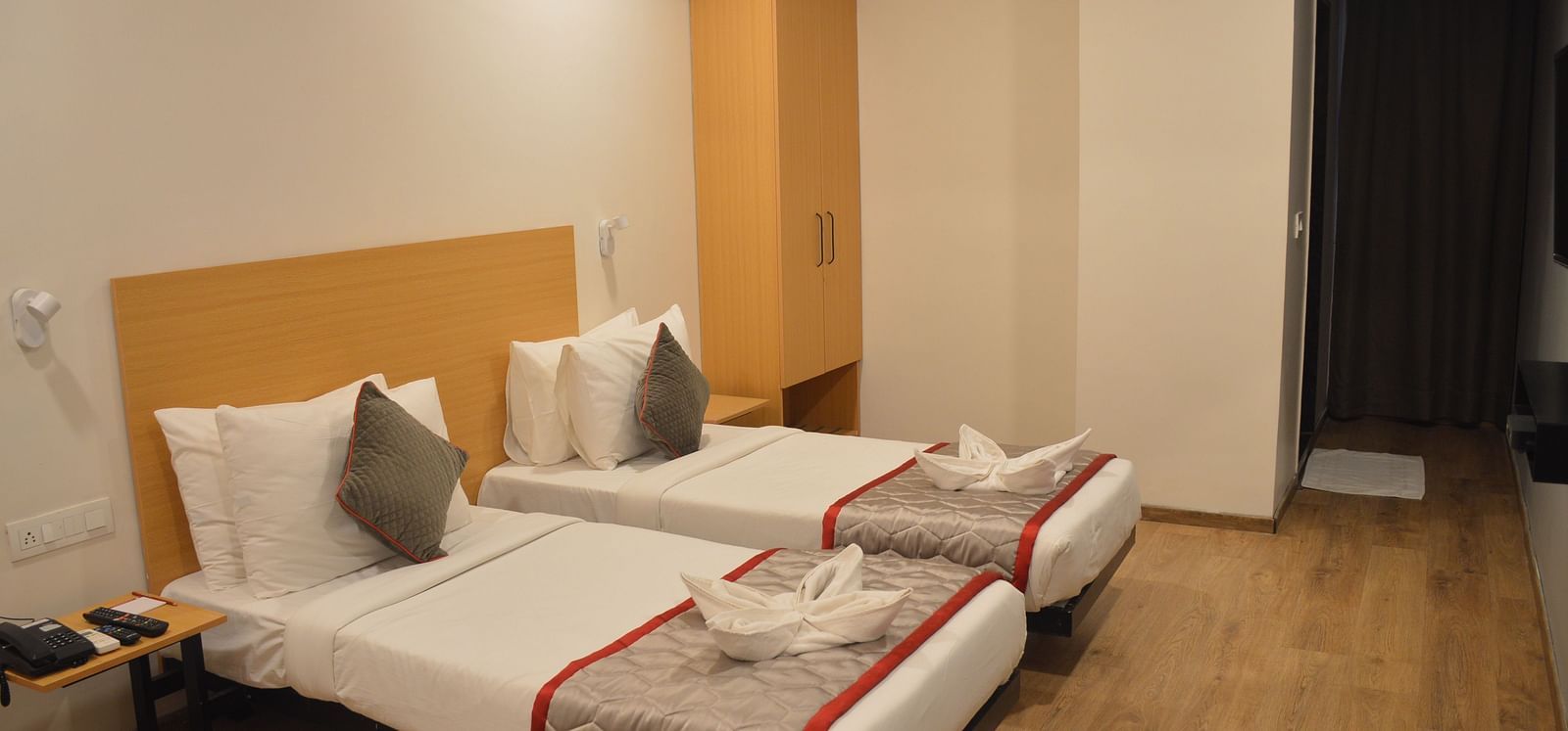 A bedroom with two single beds, air conditioning, and neutral decor - Lords Eco Inn Belagavi