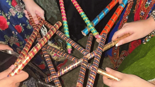 Hands holding dandiya sticks, ready to play during the traditional dance.