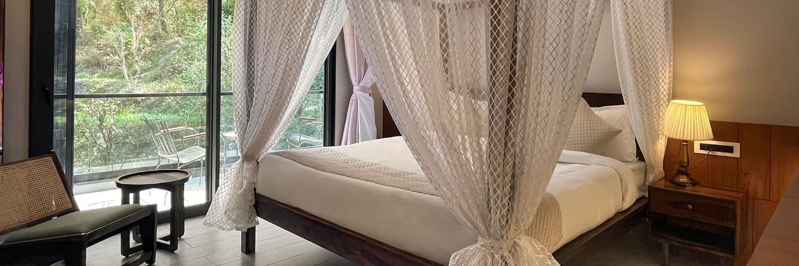 A hotel room with a beautiful bed with a glass door opening to the balcony - The Samai, Bhimtal