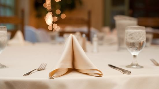 a table set with spoons, forks, napkin and more 