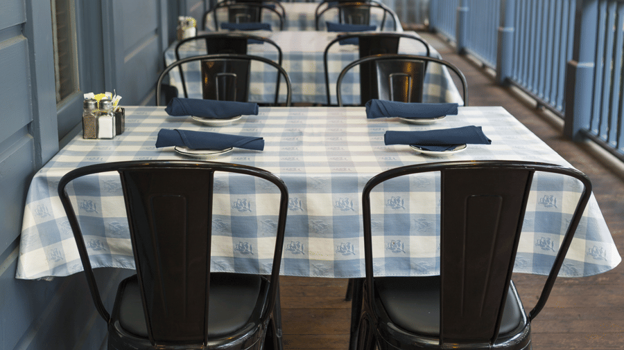 Neatly arranged dining area of Tallman Hotel at a deck with towels placed on the table.