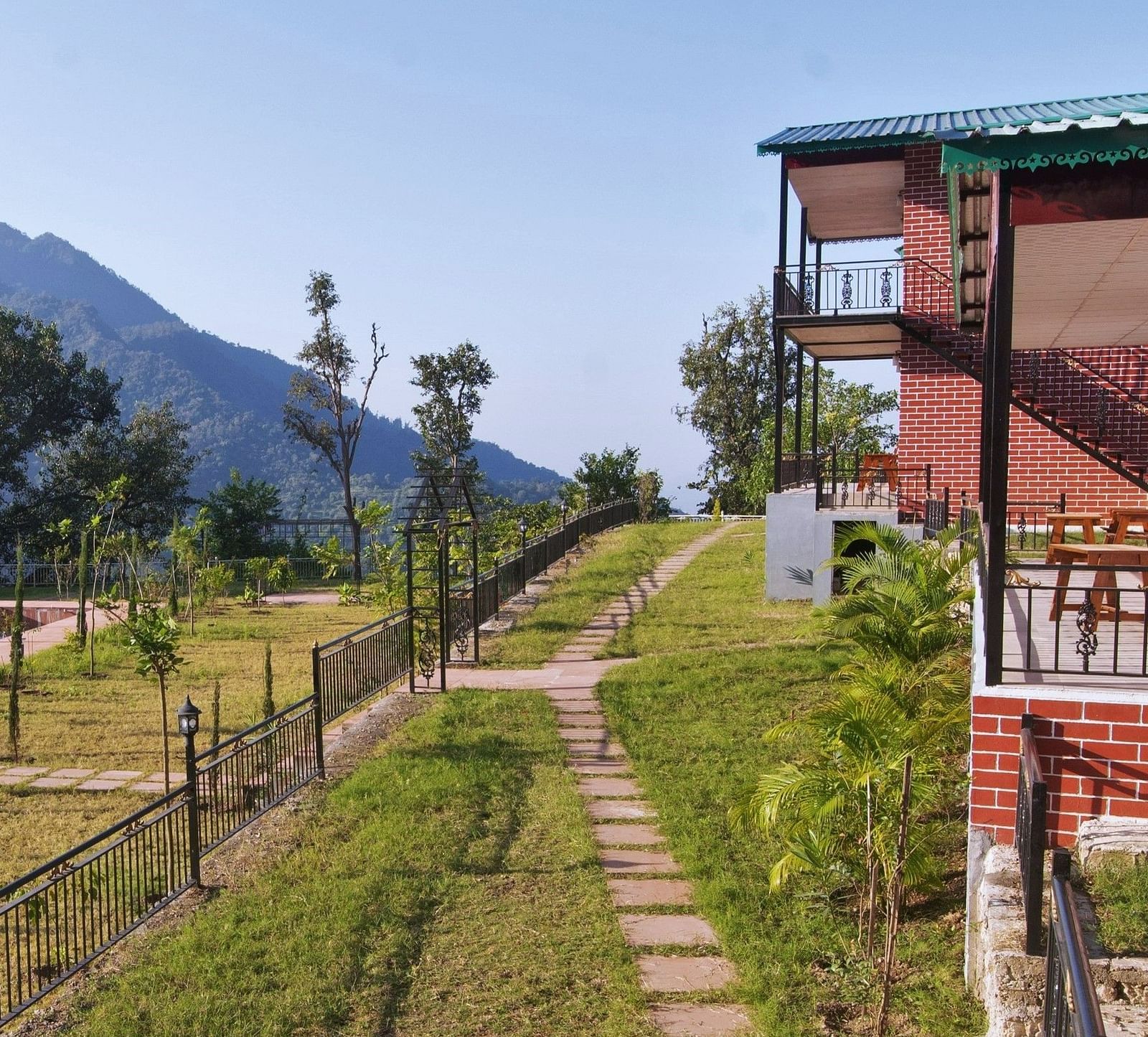 a walkway with lush green grass and stone laid lawn at Neer Ganga Resorts