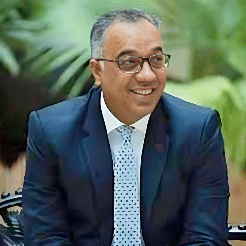 Jatin Khanna in a suit and tie, seated outdoors with greenery in the background, exuding a professional demeanor.