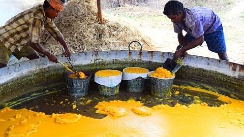 Two people making jaggery from a big pit - Black Thunder, Coimbatore