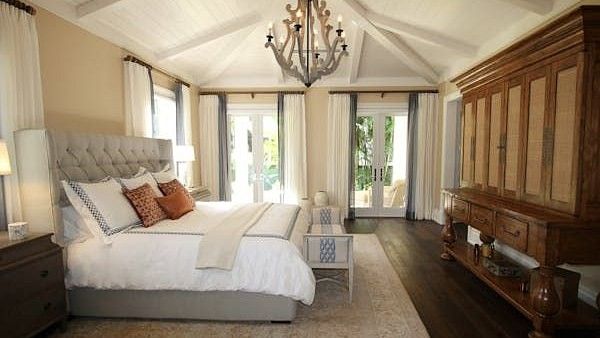 A bedroom interior with large bed and chandelier.