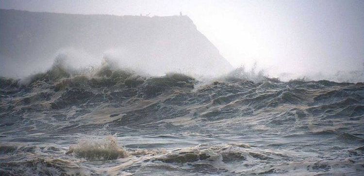 A stormy scene at Noyo Harbor with rough ocean waves crashing under a cloudy sky.