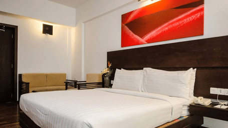 A bedroom with a king size bed, wall panel, lighting, side tables, chair, and sofa arranged indoors at Springs Hotel & Spa, J.C. Road.