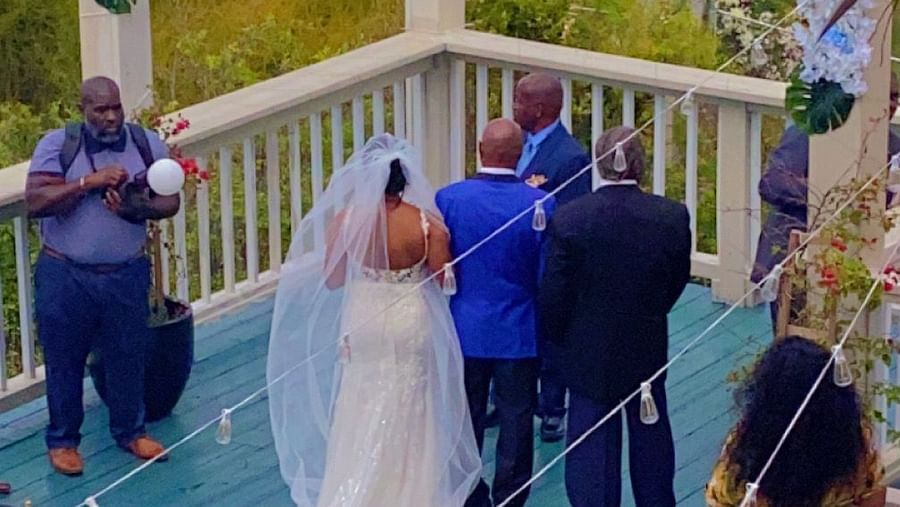 A bride walking down a wooden deck outdoors with guests present on either side | A Stone's Throw Away