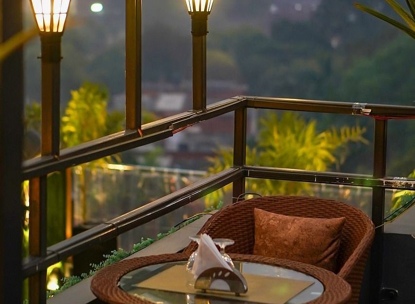 Two chairs facing each other on a terrace with warm lights beside it on a late evening.
