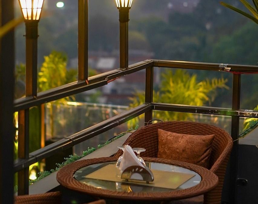 Two chairs facing each other on a terrace with warm lights beside it on a late evening.