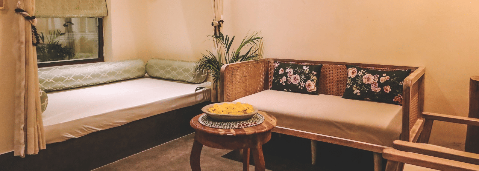 Small seating area with wooden furniture, window and wall frames at Beelwa Palace, Jaipur