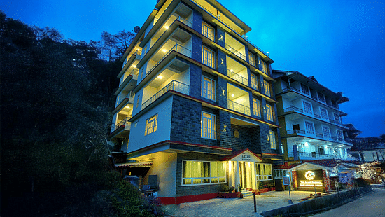 Facade of Voyage The Aryan Regency with warm sunset sky, illuminated building exterior